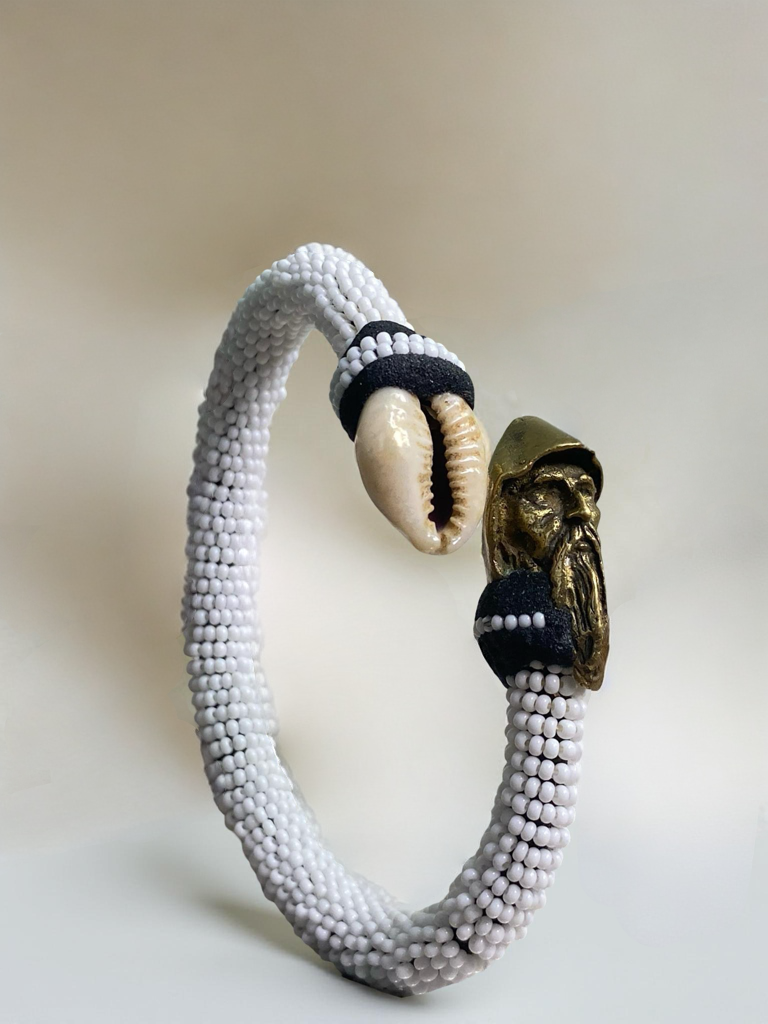 White-beaded ildé finished with a cowrie shell and a bronze elder figure