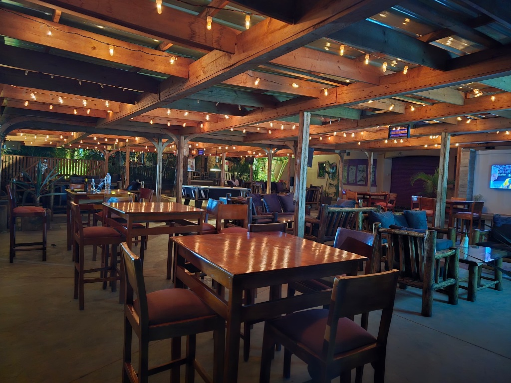 Ninaz garden lounge at dusk with warm Edison lights and flame grill