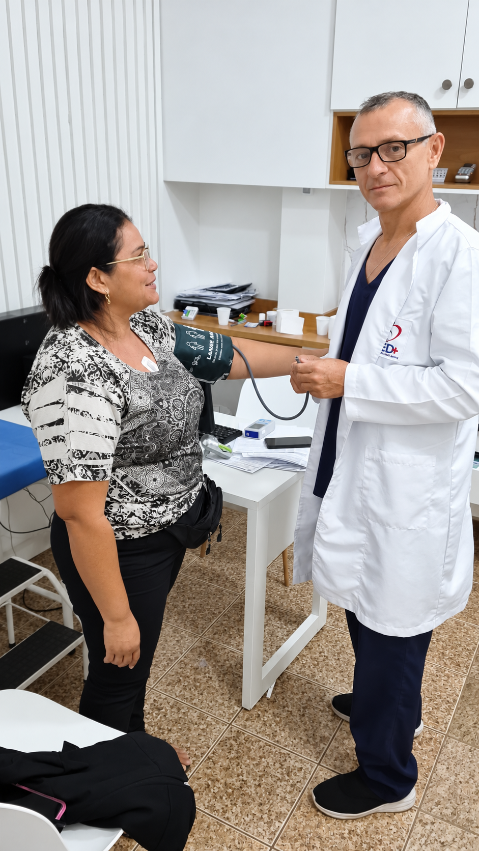 Profissional de saúde de jaleco branco medindo a pressão arterial de uma paciente com aparelho digital