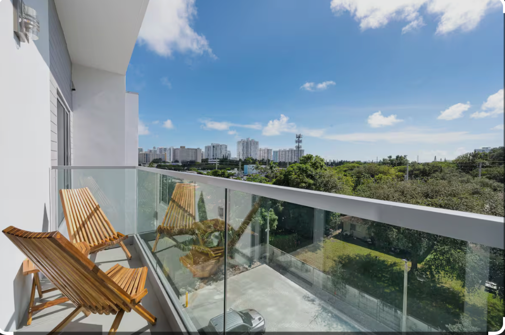 Private balcony with wooden lounge chairs and panoramic Miami skyline view