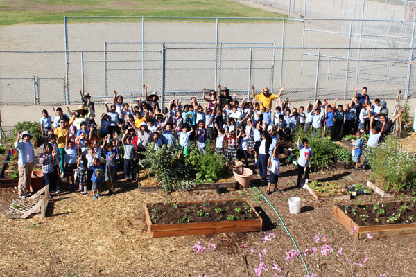 Students and teachers gathered around raised garden beds at a San Diego school garden