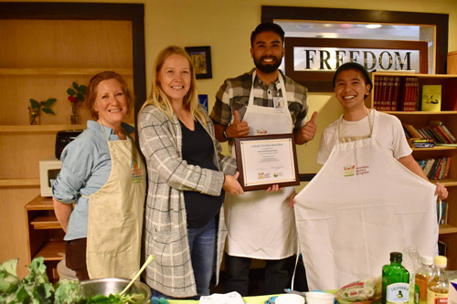 Community members in a pantry kitchen holding a framed certificate