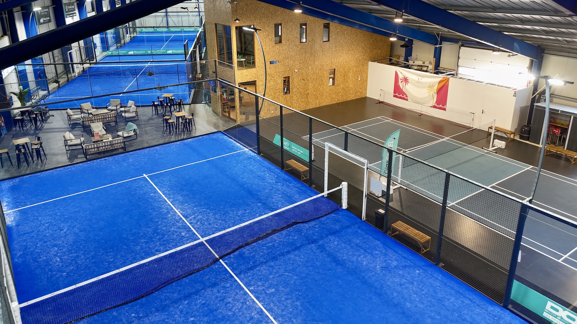Terrain de padel bleu et espace de détente au sein du club Glaz Padel à Dinard
