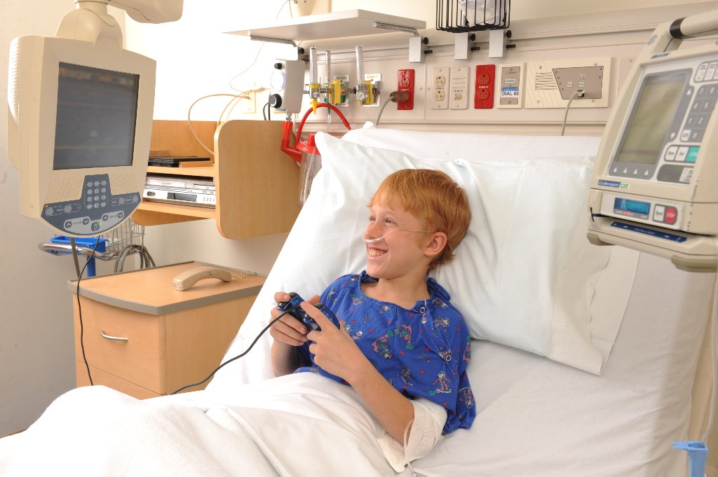 Child patient in hospital bed with video game controller