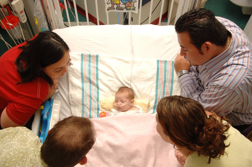 Family gathered around newborn in NICU