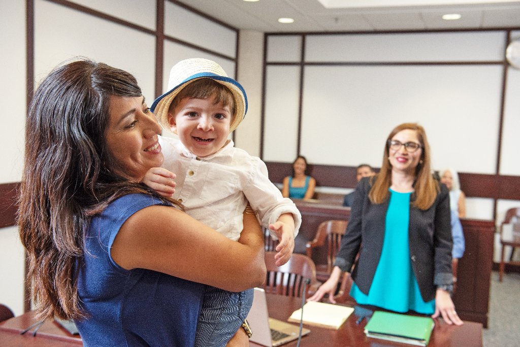 Mother and child celebrating in courtroom with attorney