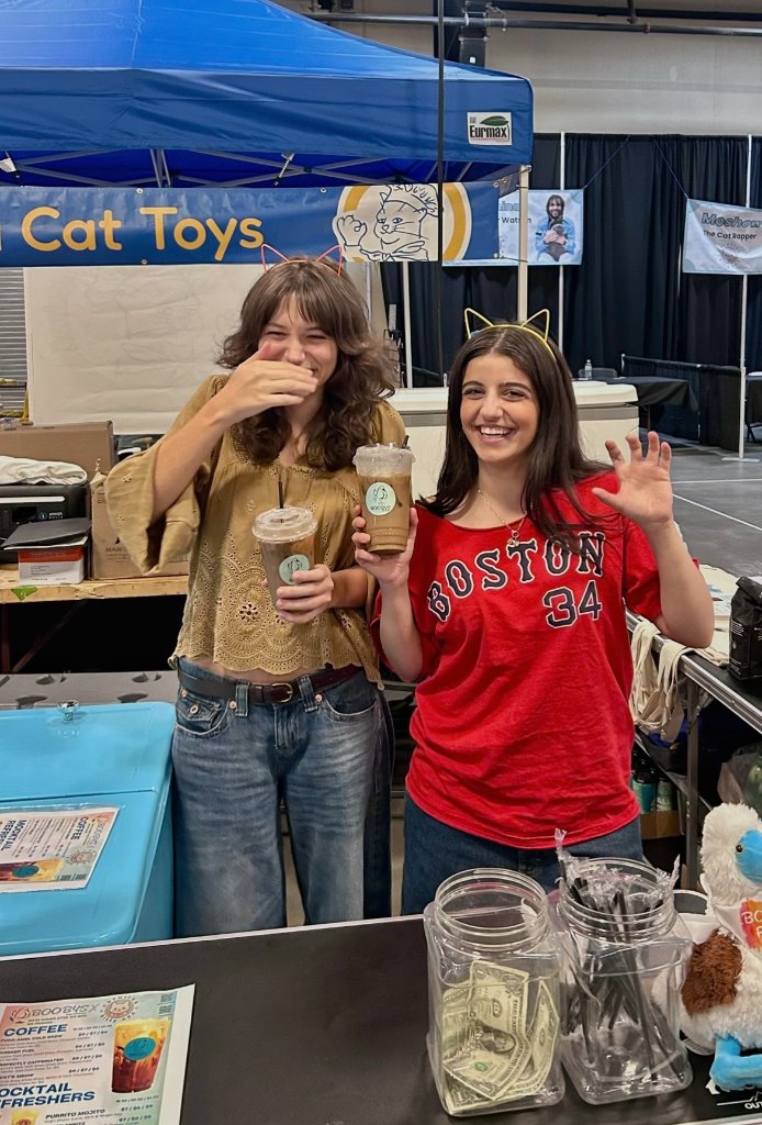 Two women behind the Boobys booth at an event