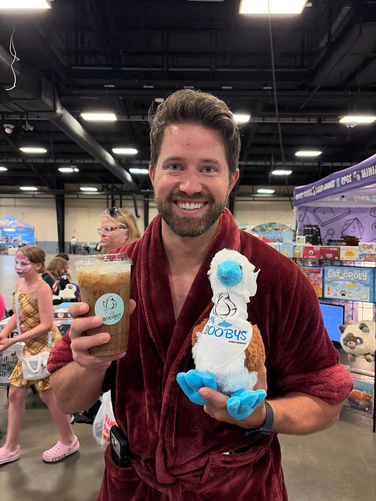 Man holding a Boobys drink and booby bird plush