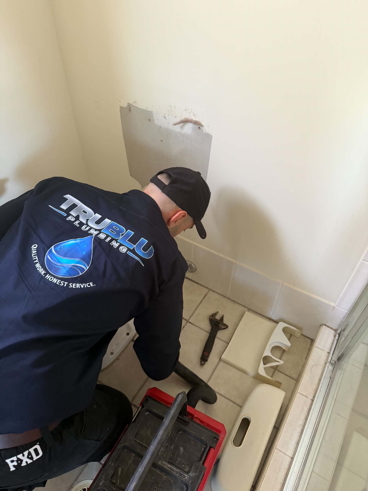 Tru Blu plumber in uniform fitting bathroom fixtures on a local job