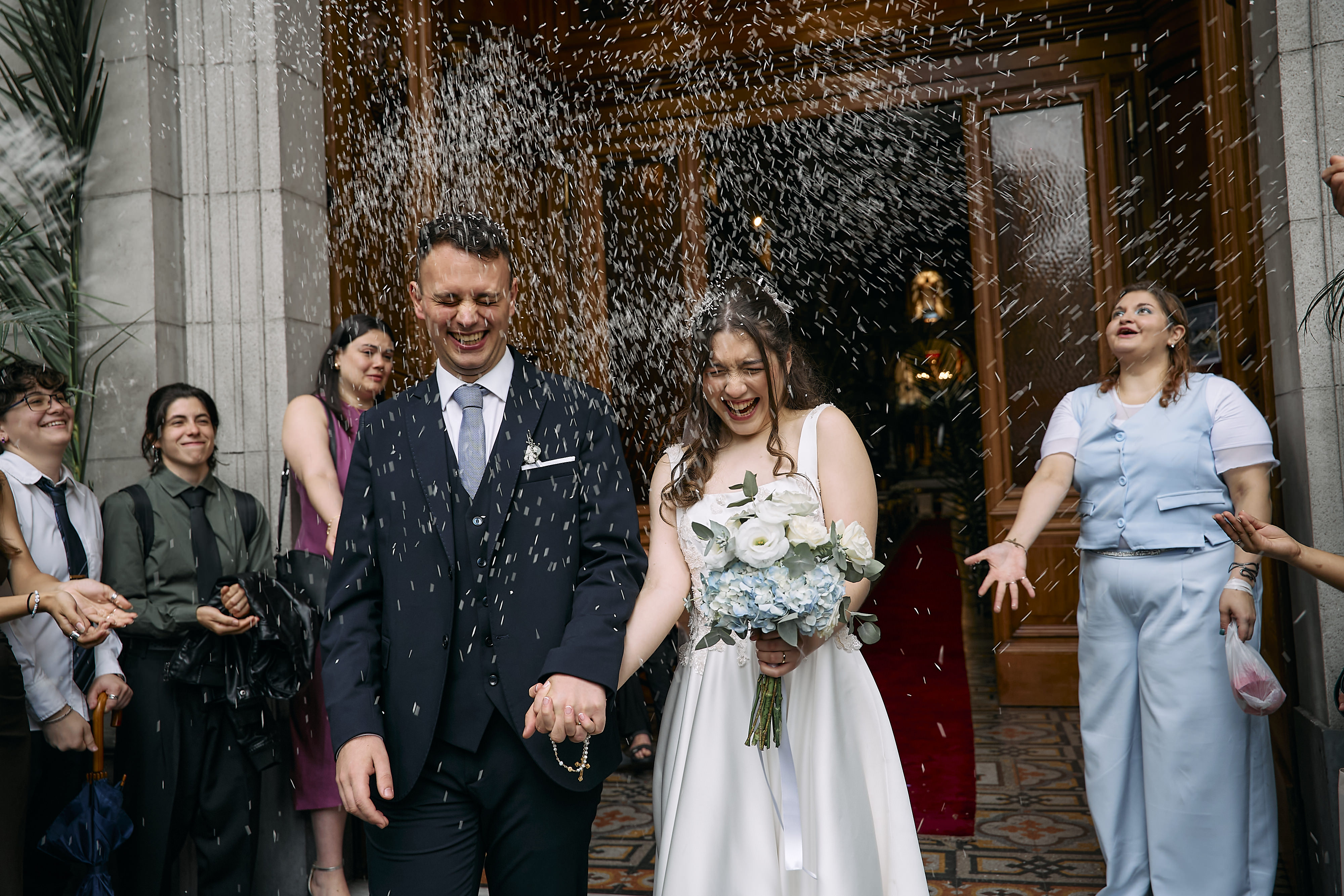 Los novios saliendo de la iglesia entre una lluvia de arroz lanzada por los invitados