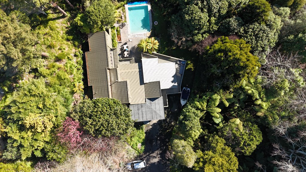 Aerial view of the property before solar installation, showing the house in a tree-filled gully with no panels on the roof