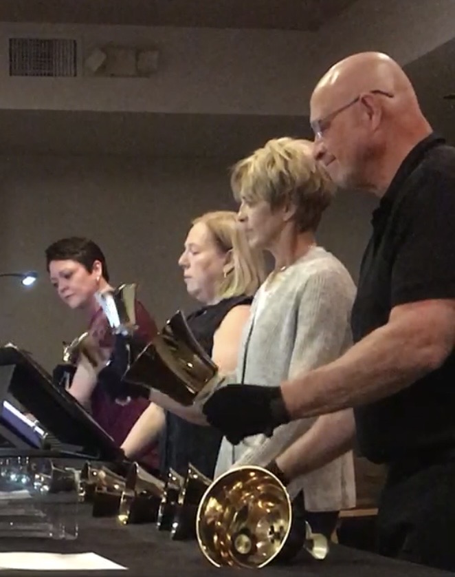 Handbell choir performing with polished brass bells