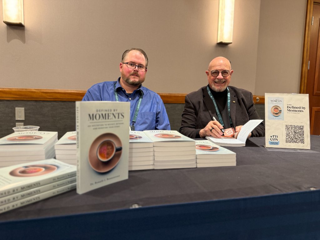 Ron Bonnstetter signing copies of Defined By Moments at a TTI Con 2026 book signing event