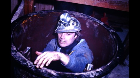 Ron emerging from a cave opening wearing a mining helmet