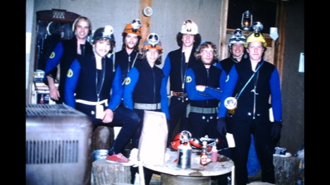 Group of eight caving students in helmets and jumpsuits