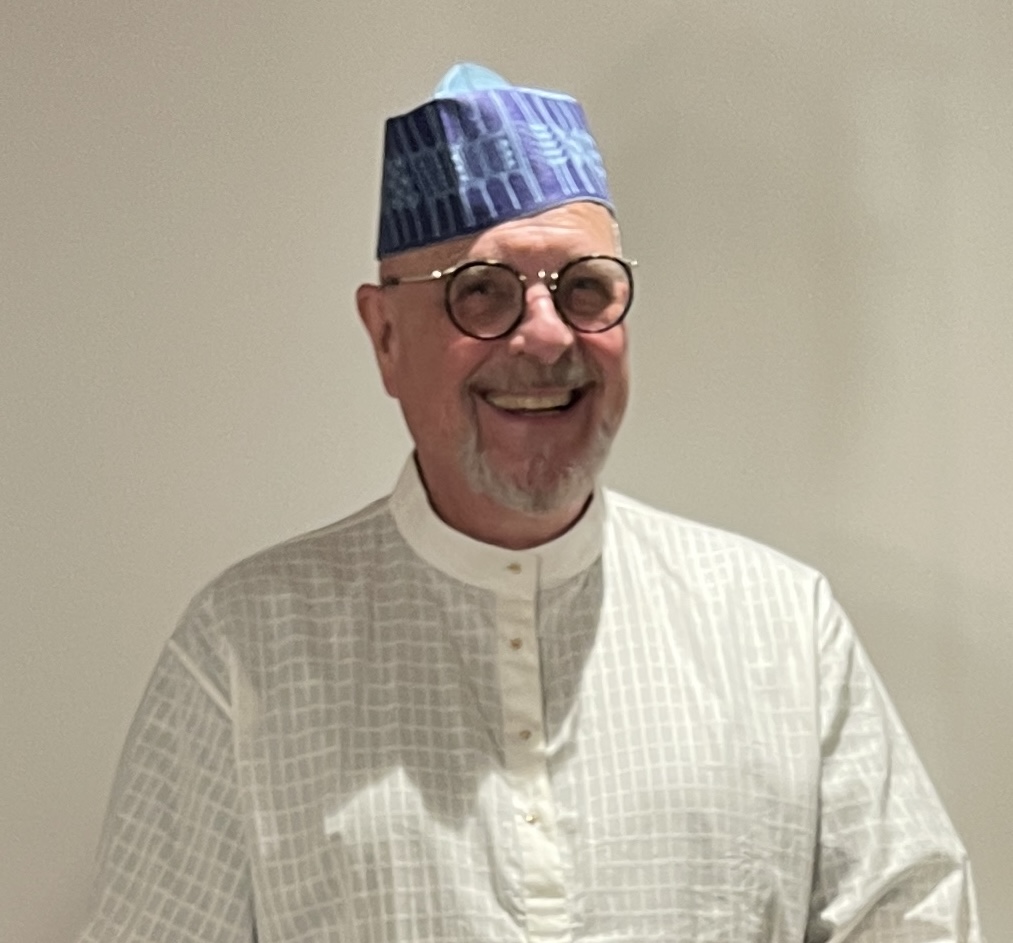 Ron wearing a traditional blue and white patterned West African cap