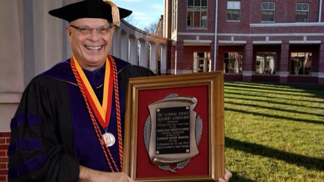 Ron Bonnstetter in academic regalia holding the National Science Teachers Association award plaque