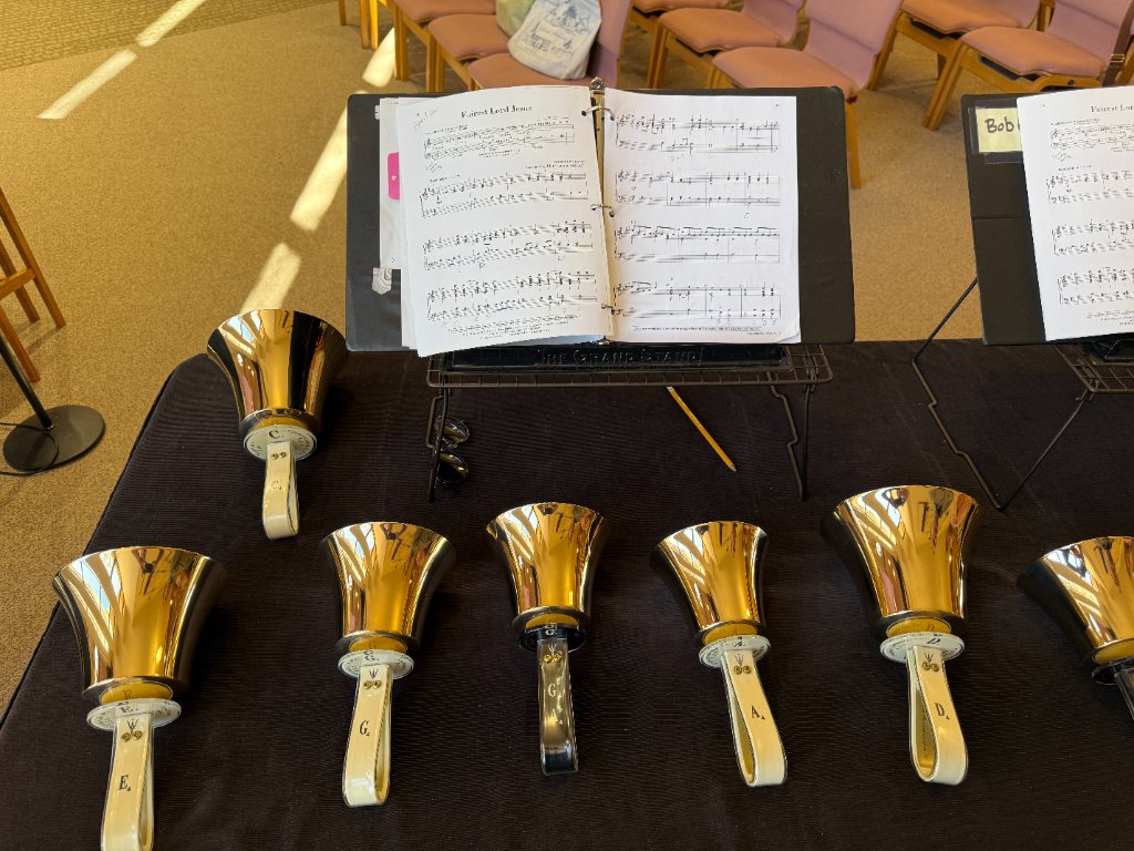 Handbells arranged on a table with sheet music for a bell choir performance