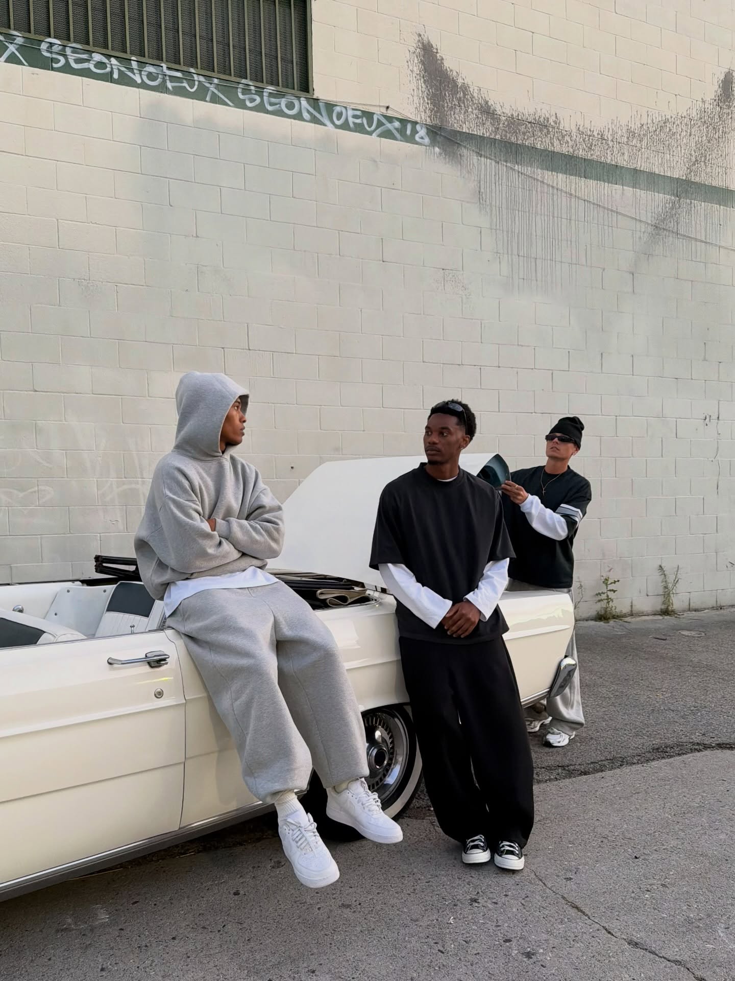 Custom streetwear apparel showcased by a group around a car