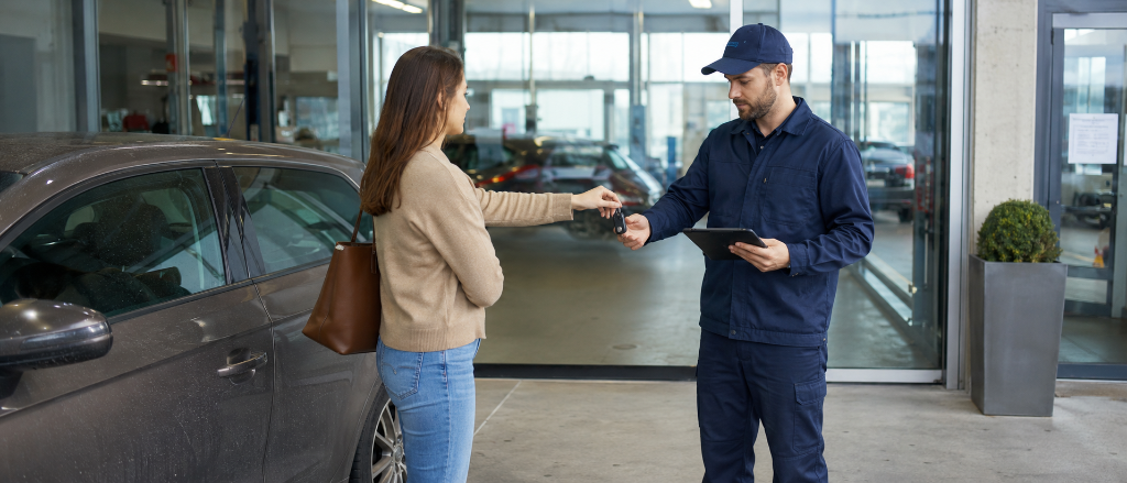 Cliente remet ses clés à l'employé de garage qui enregistre l'arrivée sur tablette