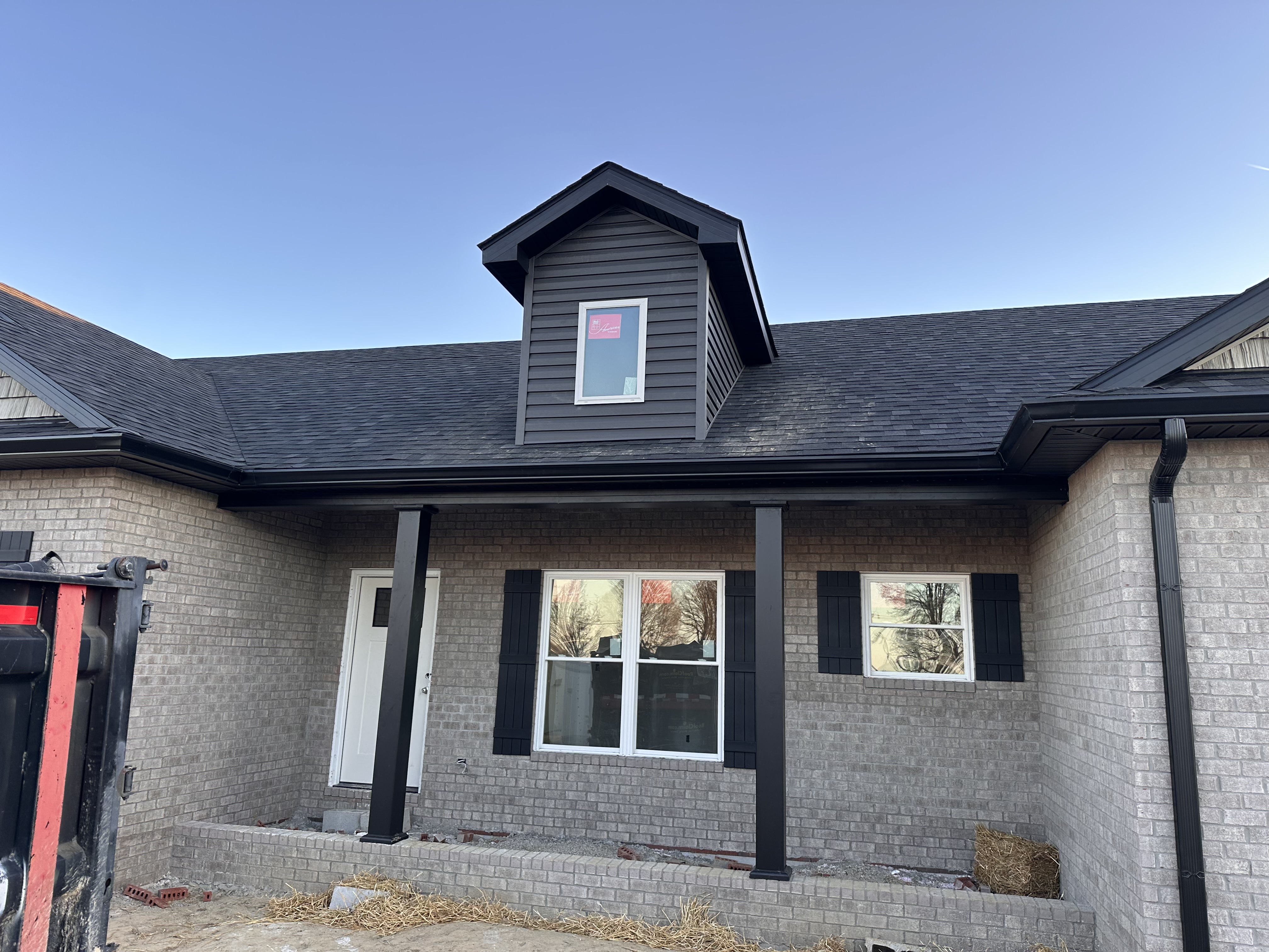 Black seamless gutters installed on a gray brick home