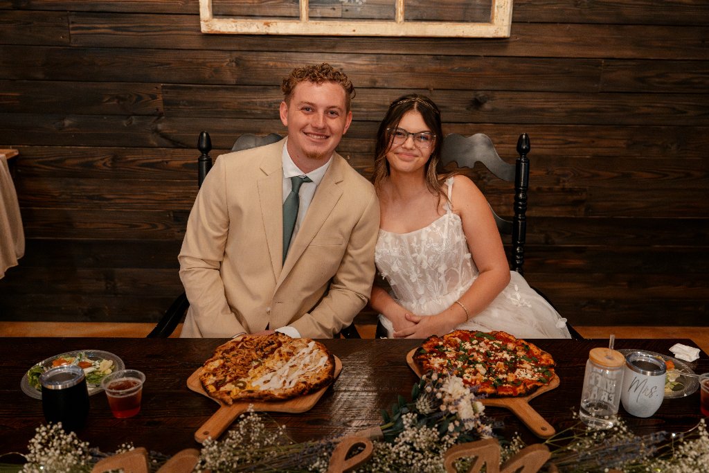 Newlyweds with wood-fired pizza at their reception