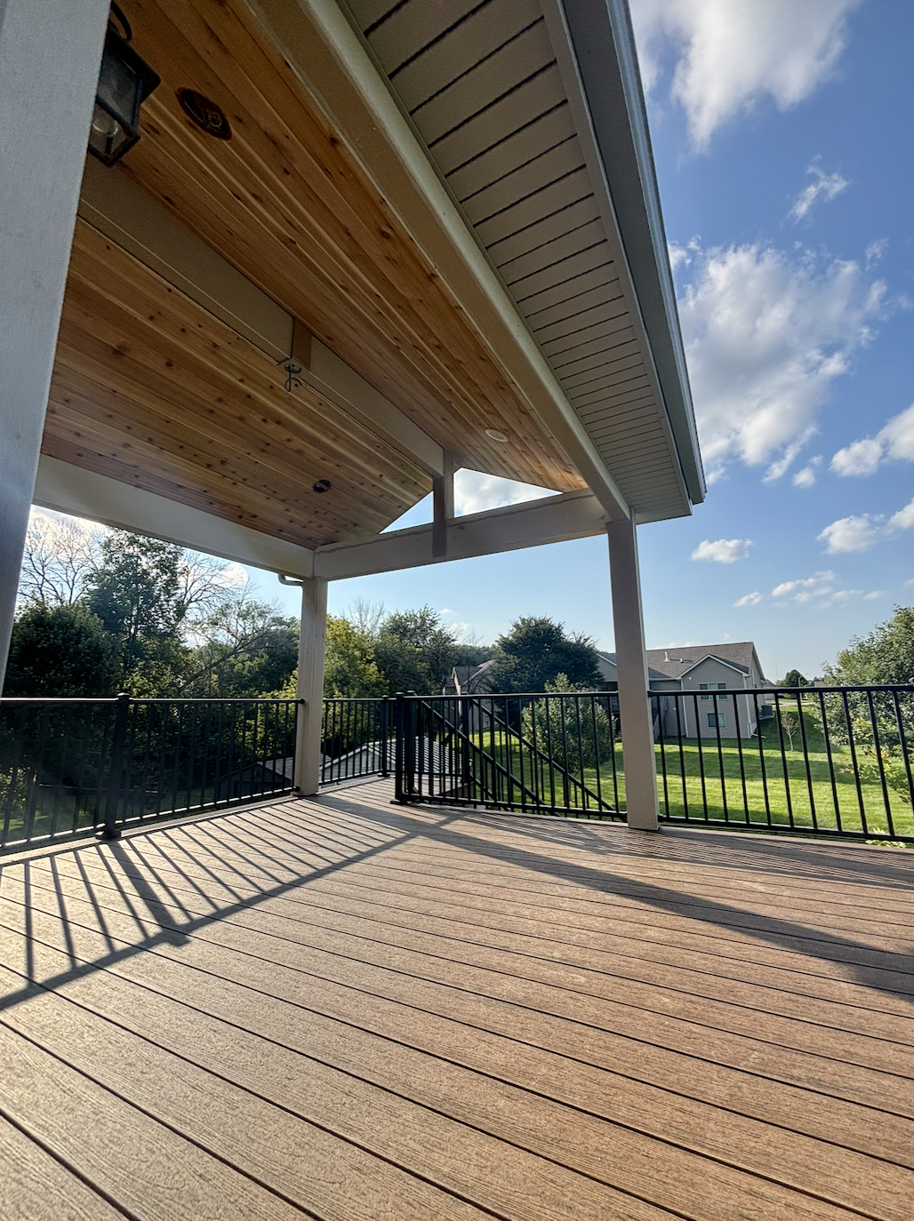 Covered composite deck interior with TimberTech Reserve boards, wood ceiling, and recessed lighting in Ankeny