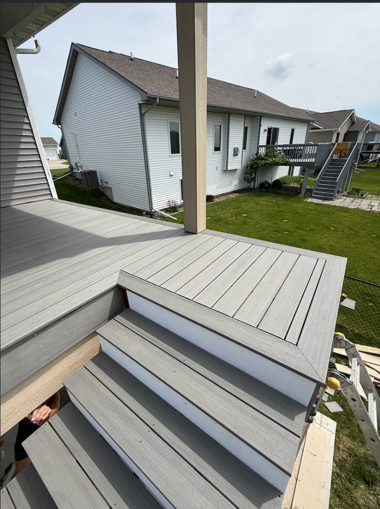 After - Composite deck steps and landing detail with gray TimberTech Prime+ boards and white PVC risers by deck builder Akin Brothers Construction in Ankeny, Iowa