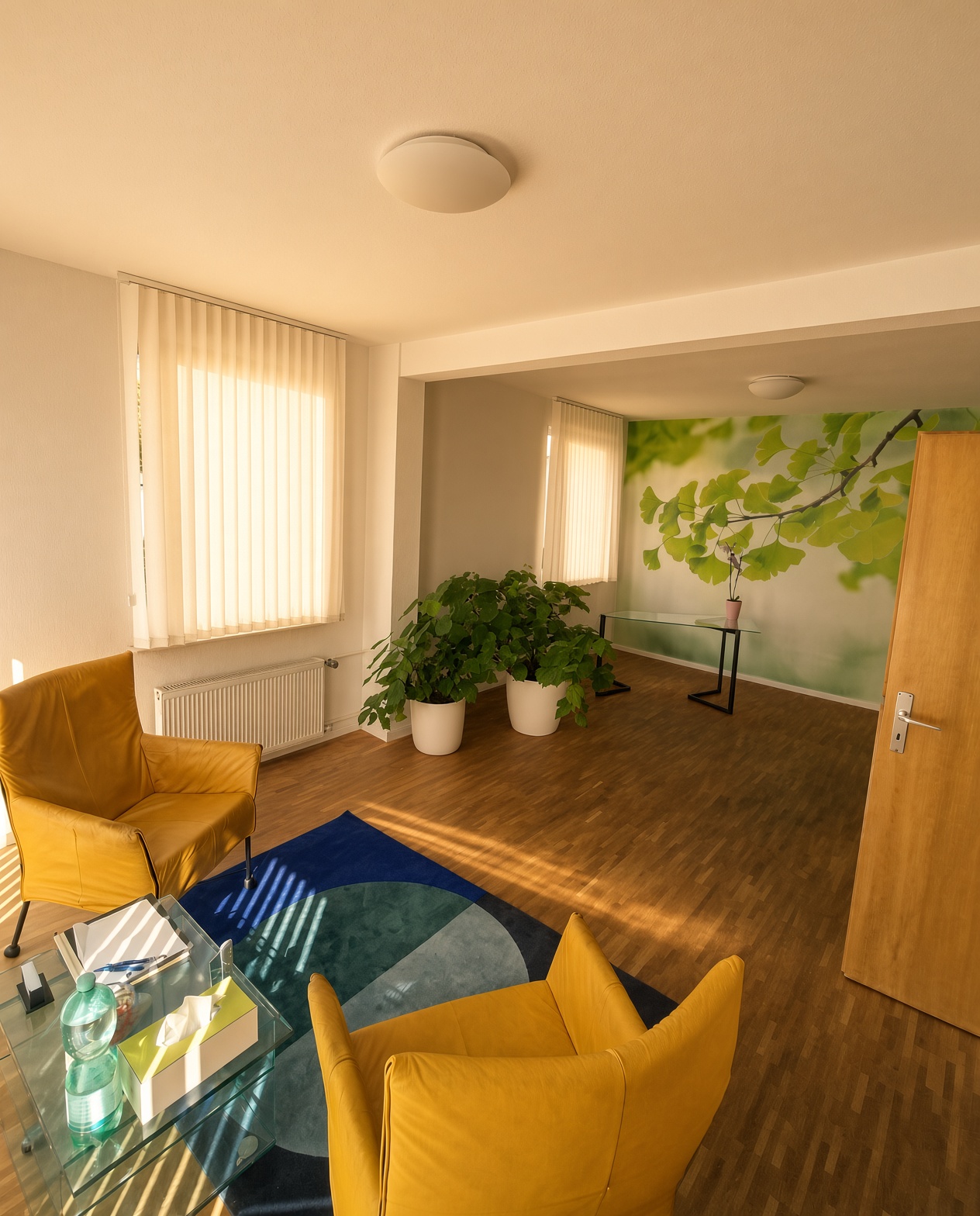 Praxisraum von Kristina Beste – Psychotherapie Kassel mit Sitzecke und Ginkgo-Wandbild