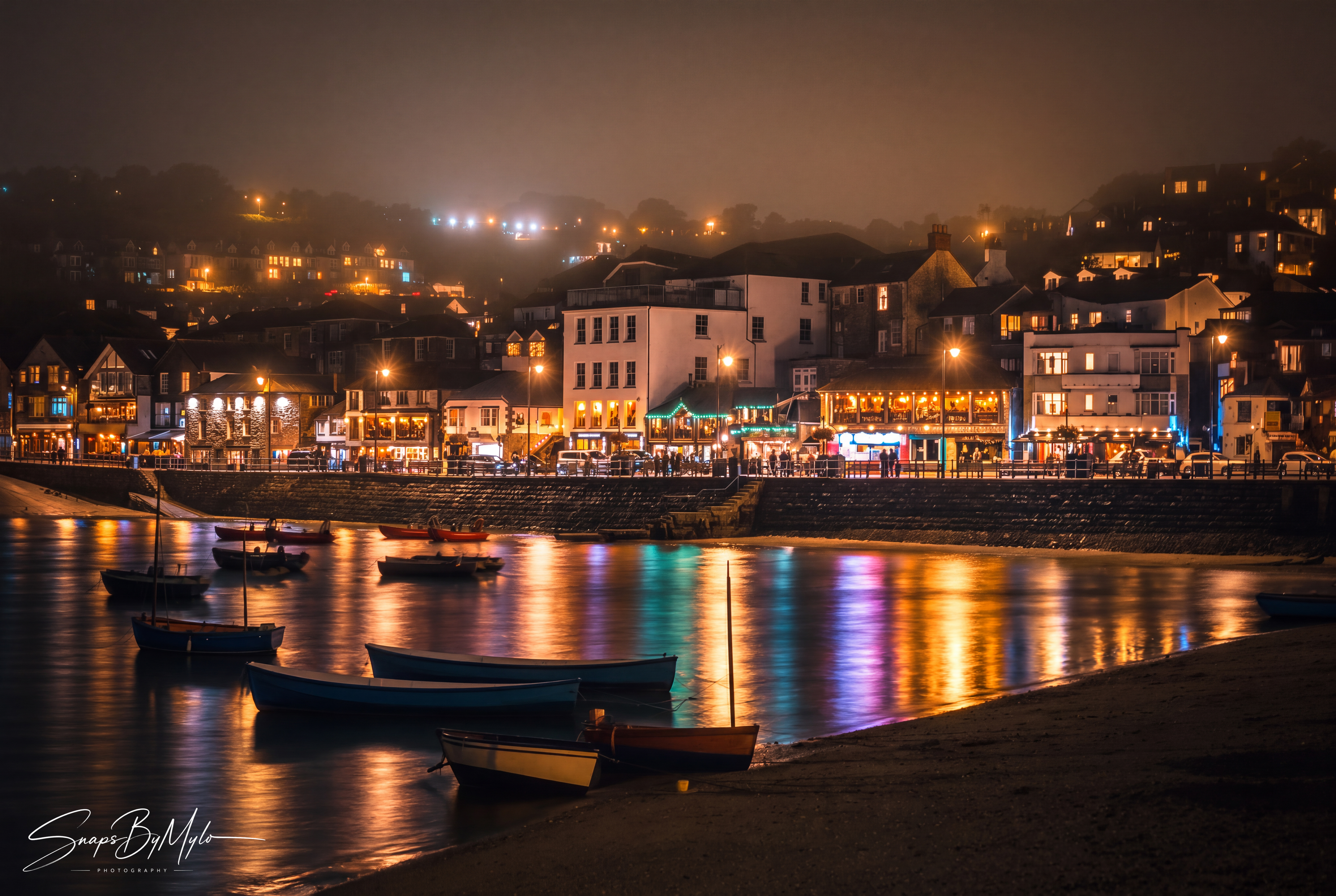 St Ives harbour at night, with warm lights reflecting in the still water