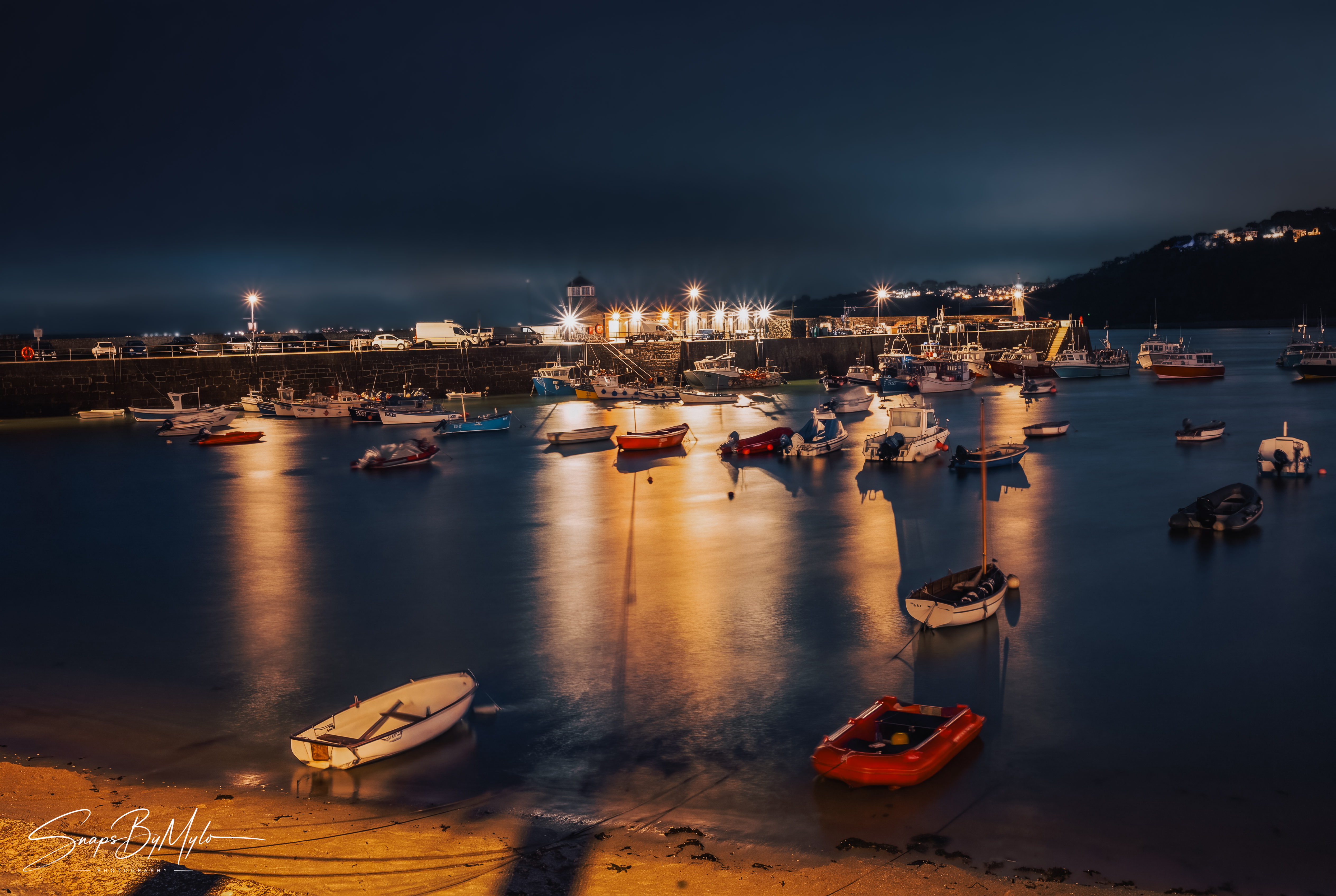 Long-exposure night photograph of St Ives harbour, boats and reflected lights