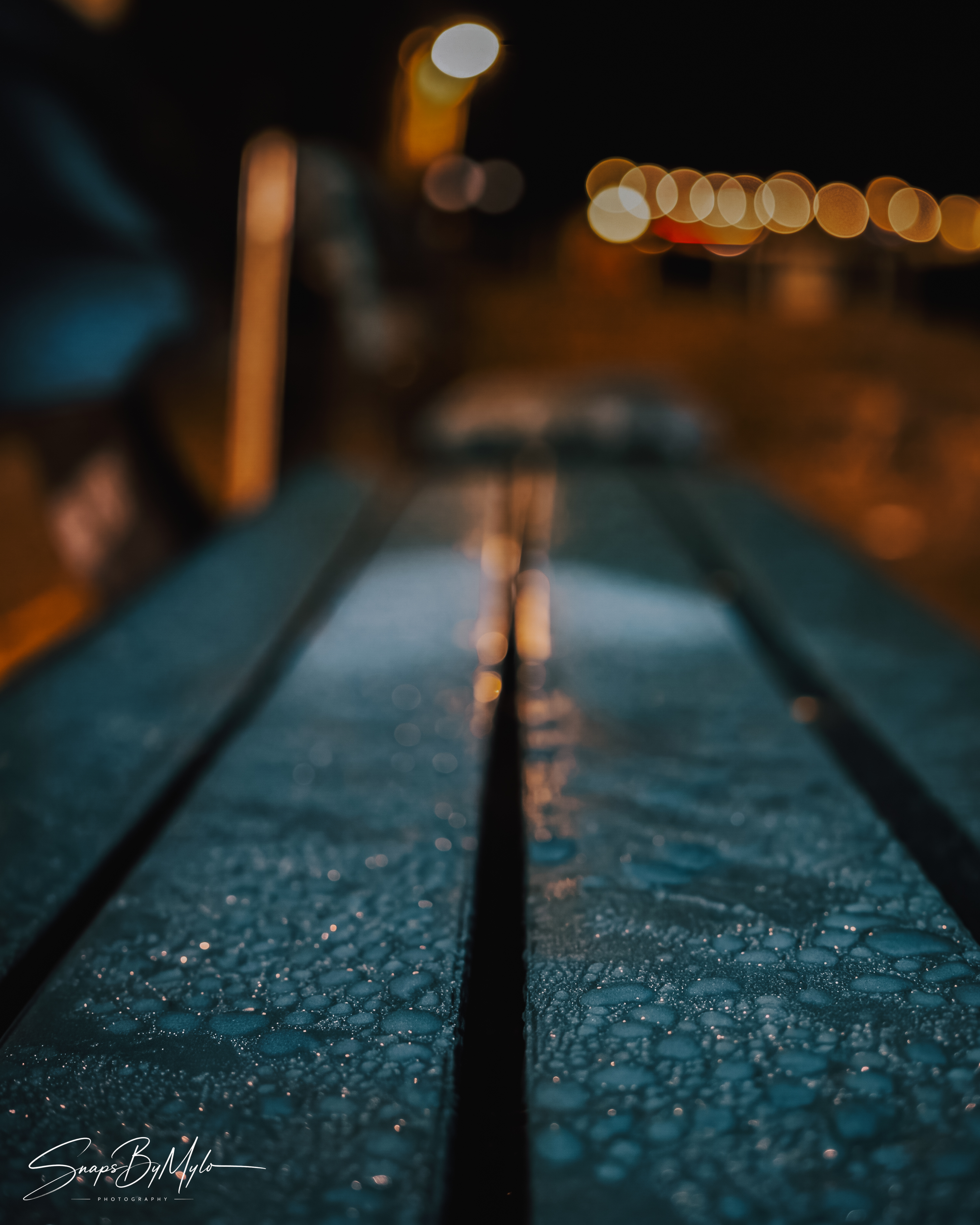 Close-up of wooden planks covered in morning water droplets, with warm bokeh in the background