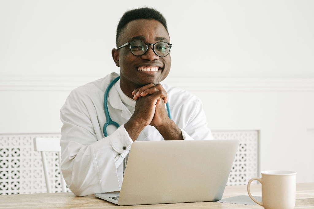 Médecin souriant devant son ordinateur, serein et disponible