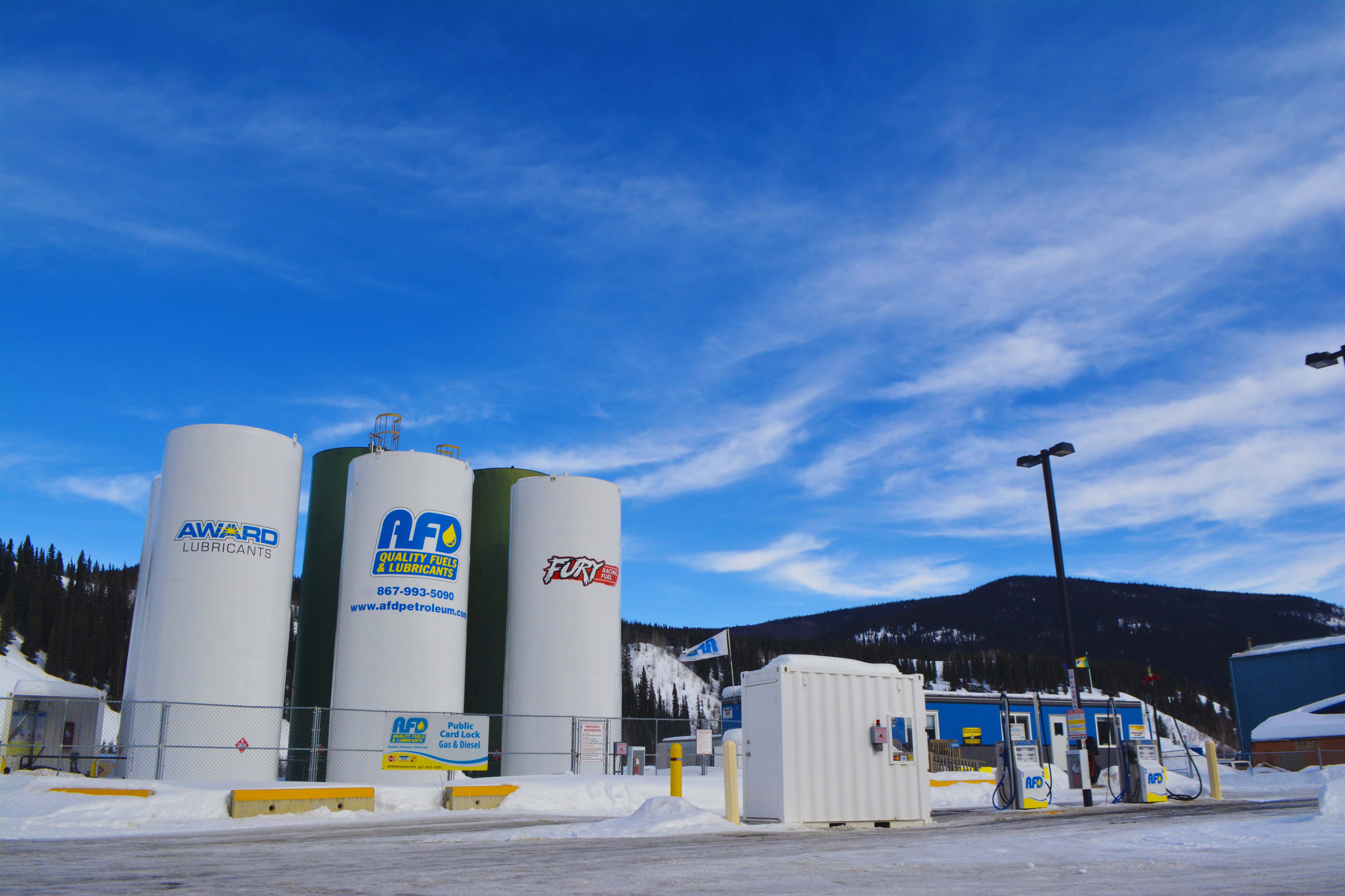 AFD Petroleum fuel storage tanks and office unit in a snowy Yukon yard with mountains behind