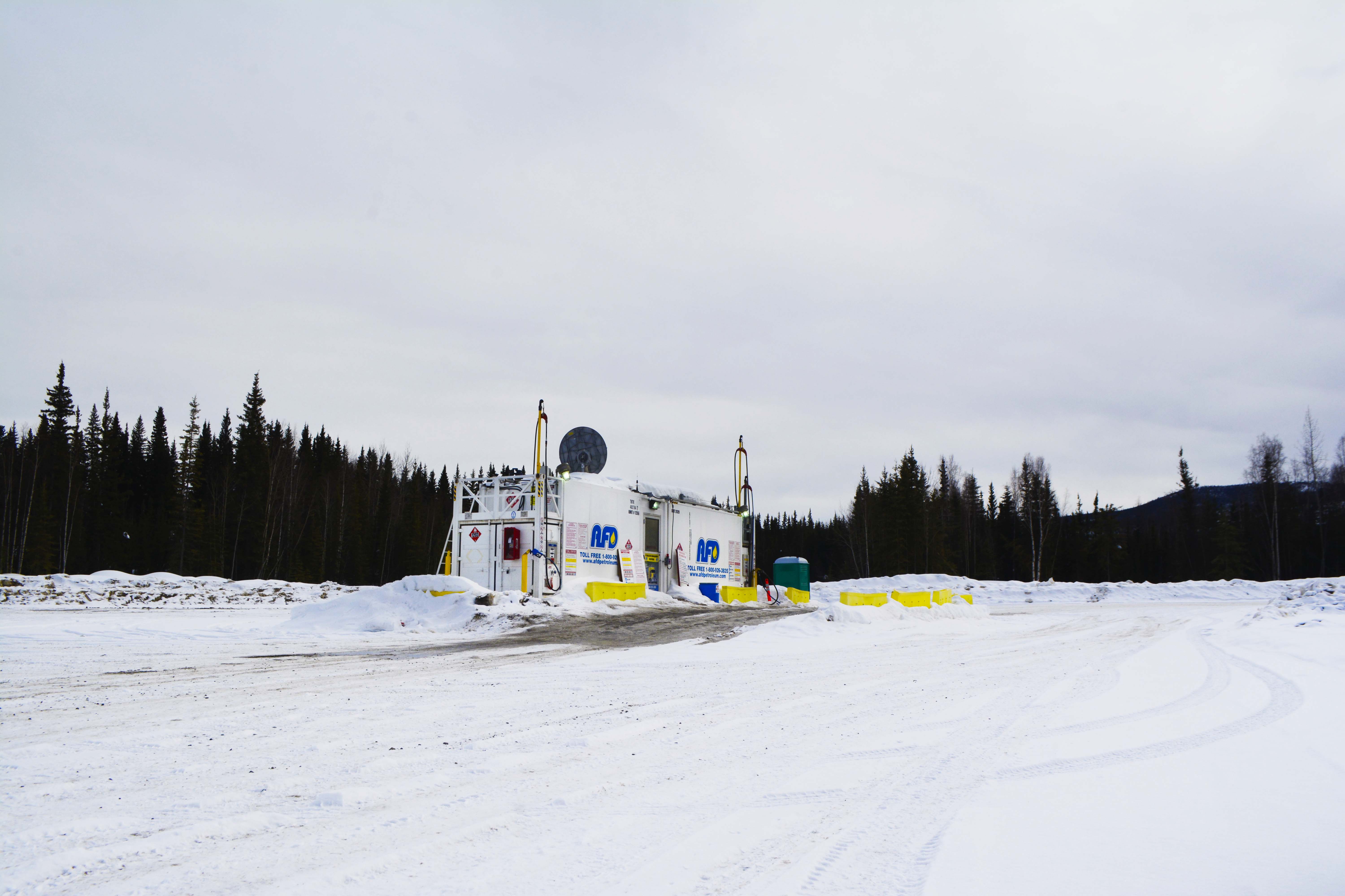 White AFD Petroleum modular refueling unit with dispensers and yellow barriers in a snowy Yukon yard