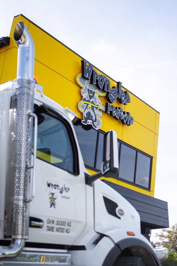White Peterbilt water tanker parked in front of modern commercial building