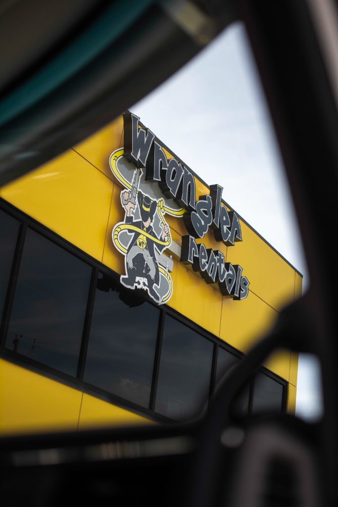 Low-angle view of Wrangler Rentals building signage from inside a vehicle