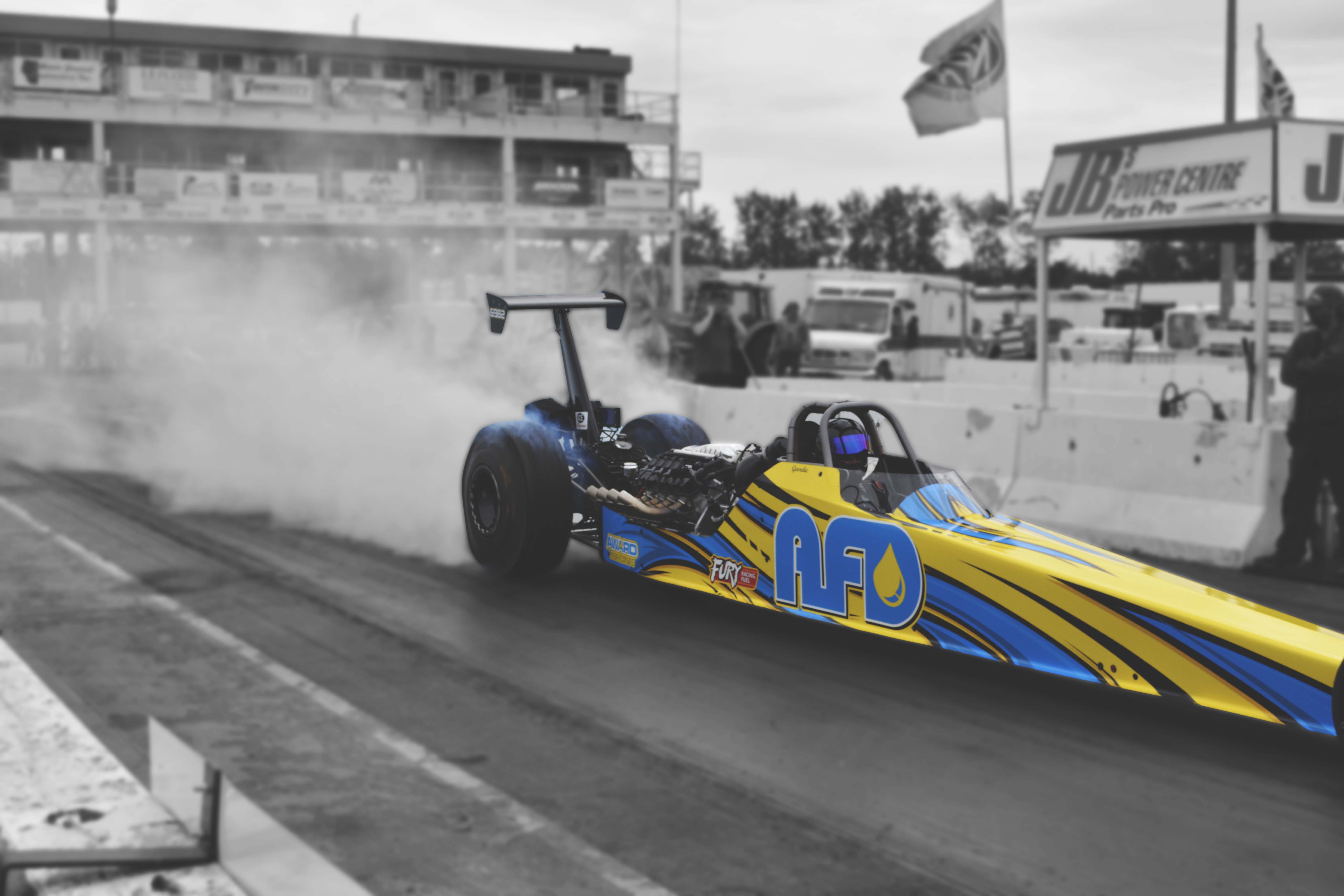 AFD Petroleum dragster doing a burnout with white smoke on the track