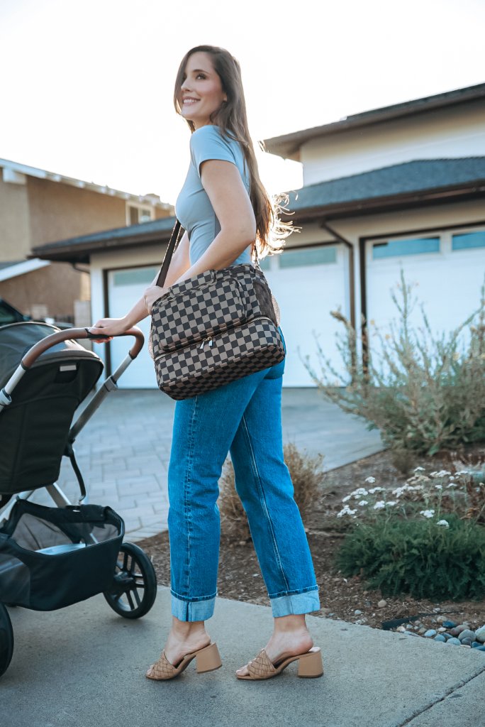 Parent carrying JOONI bag as shoulder tote while pushing stroller