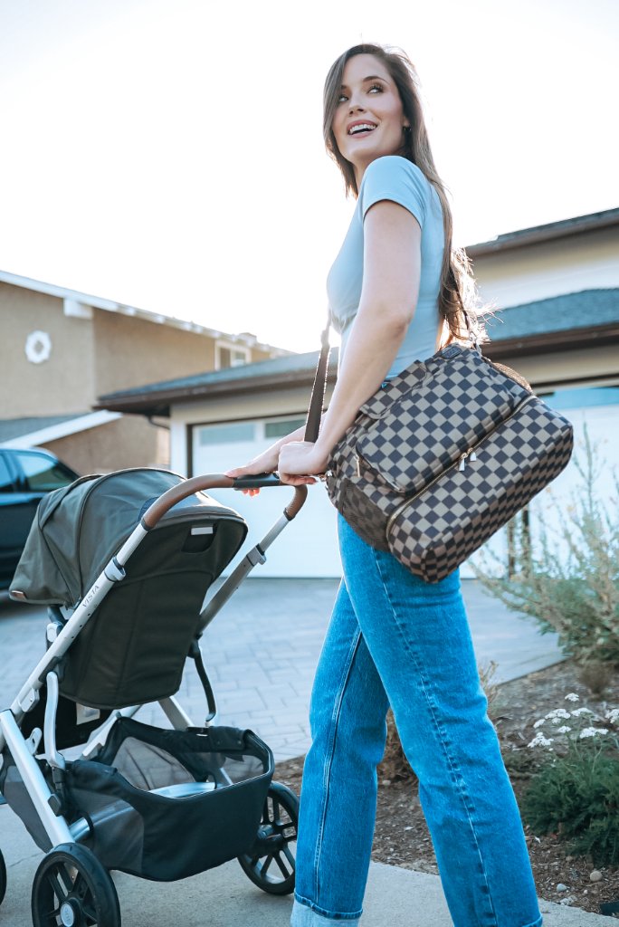 JOONI diaper bag caddy carried as a stylish shoulder tote by a parent in an urban park