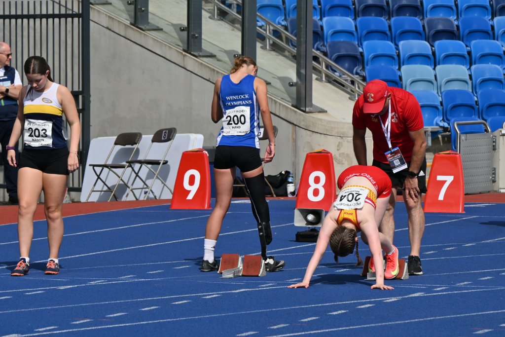 Two female hurdlers clearing barriers simultaneously on the track