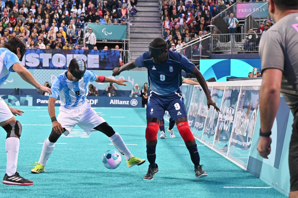 France No.9 battles Argentine player along sideline boards at Paris 2024 blind football final