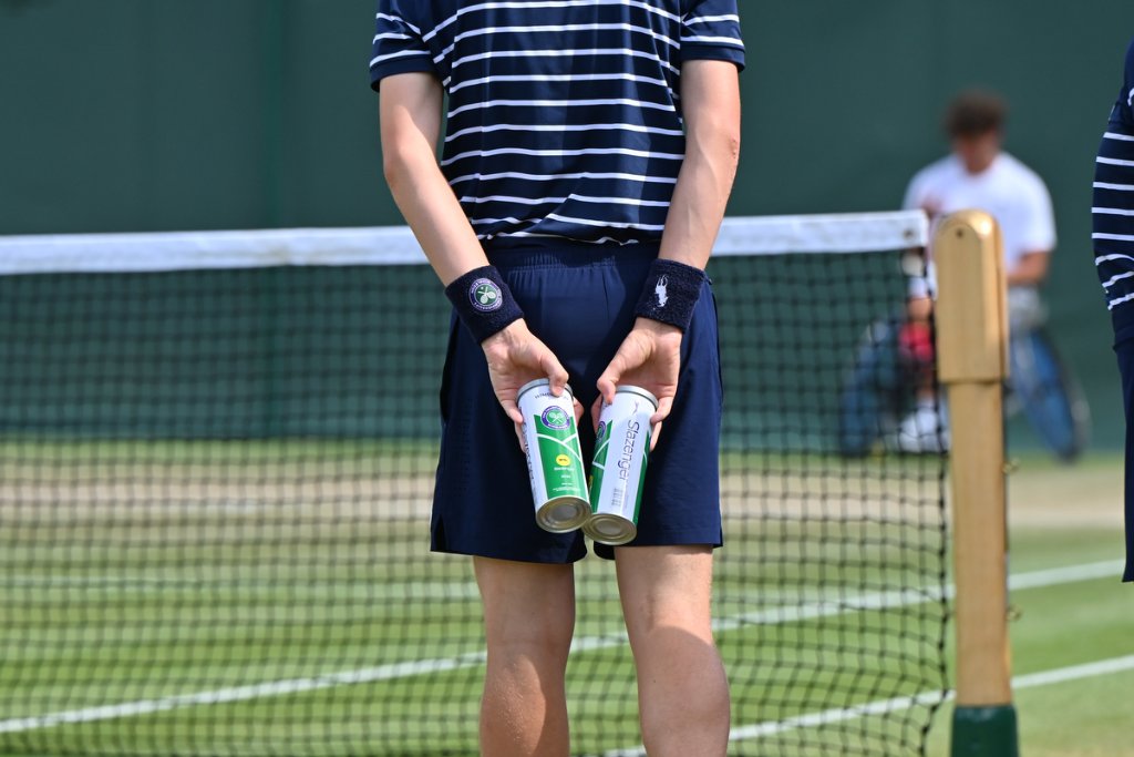 Ball boy holding Slazenger Wimbledon ball canisters at the net