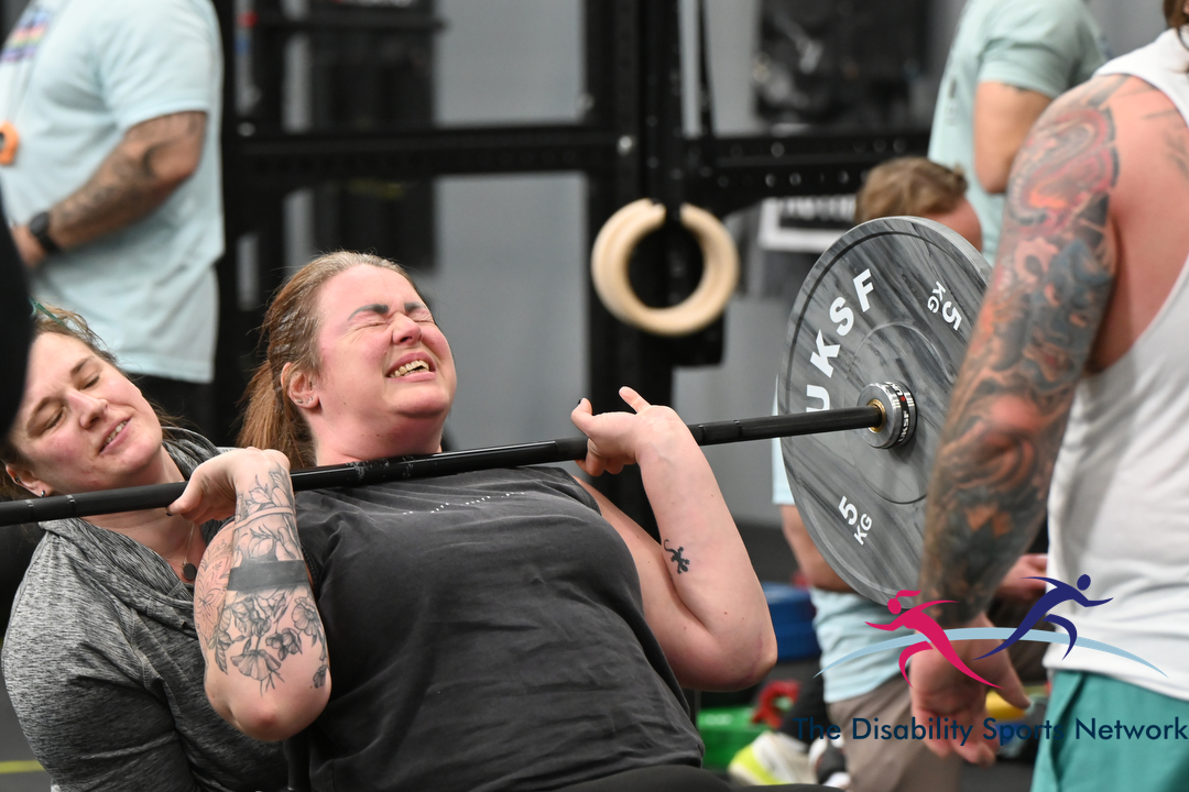 Athlete completing a barbell lift with a spotter helping at Alt Movement