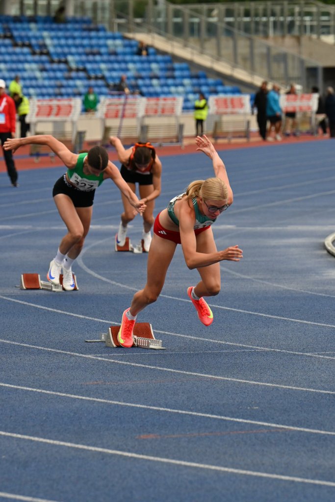 Three female sprinters exploding from starting blocks