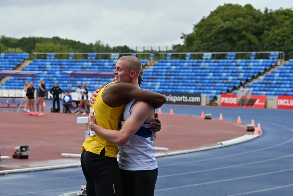 Two male athletes hugging on the track after their race