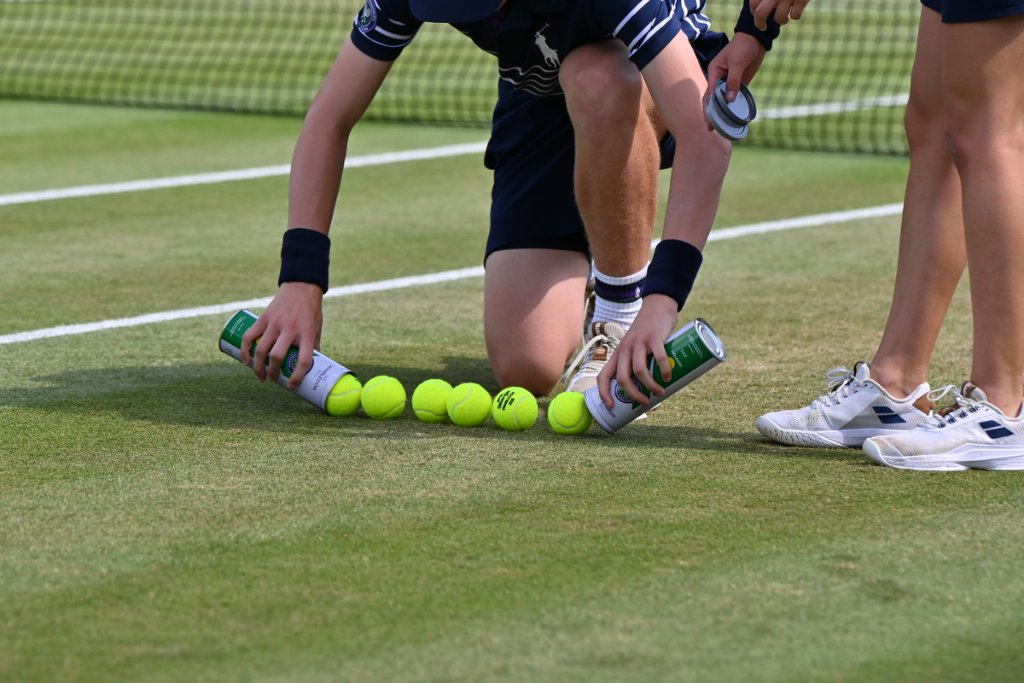 Ball boy lining up six tennis balls on the Wimbledon grass court