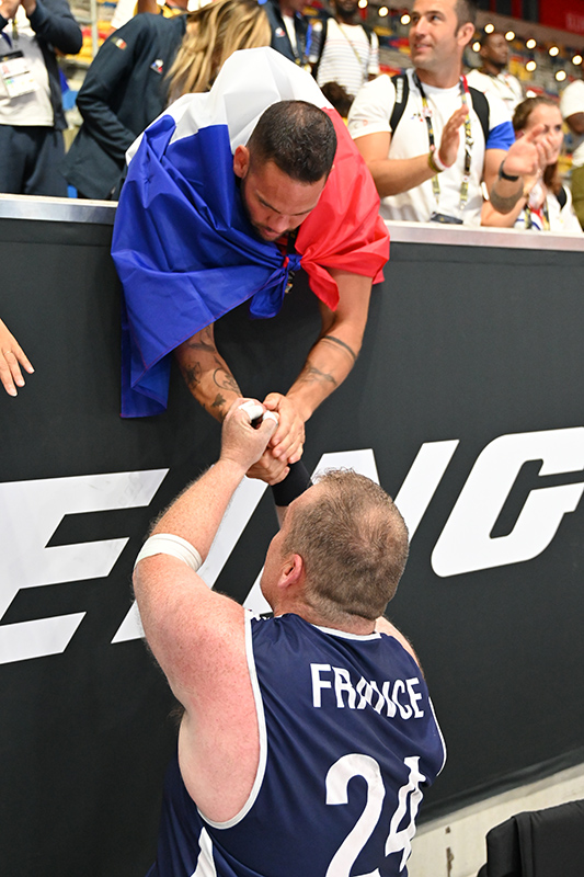 French wheelchair rugby player clasping hands with a fan in the stands after a match