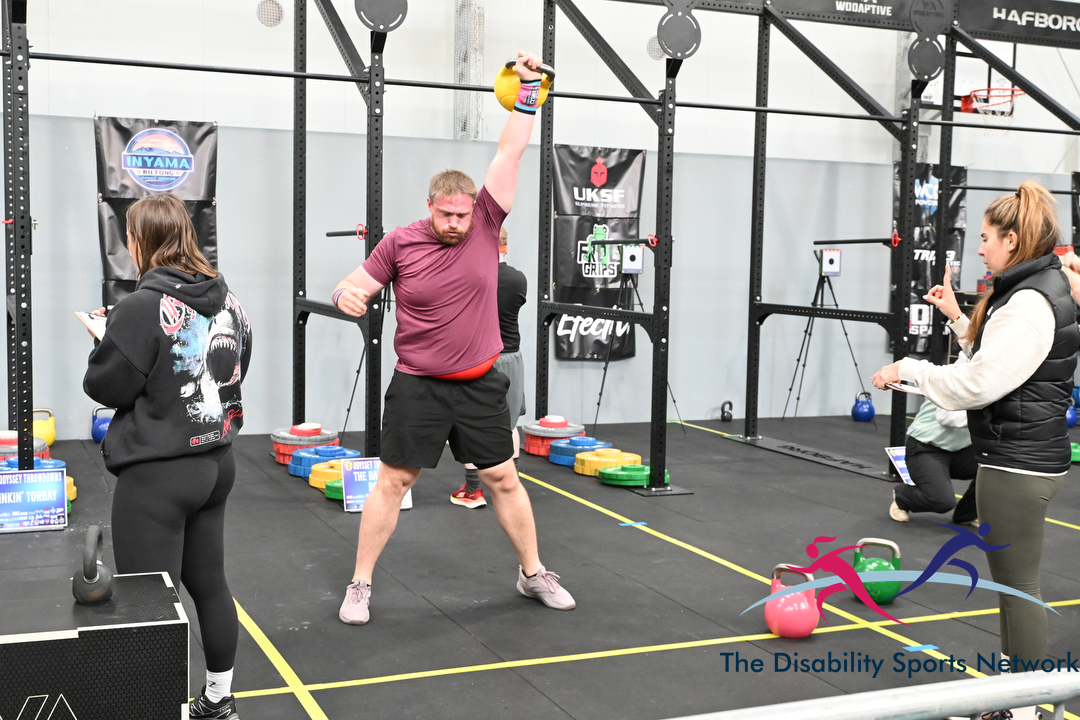 Athlete performing a one-arm kettlebell snatch as judges look on at Alt Movement