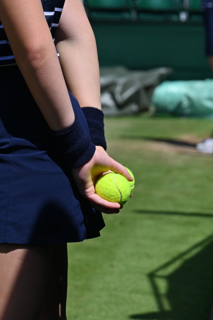 Wimbledon ball girl holding tennis ball on the grass court